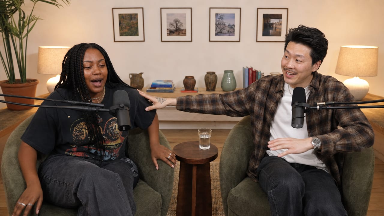 Two podcast hosts getting up out of their chairs at the end of a recording, laughing
